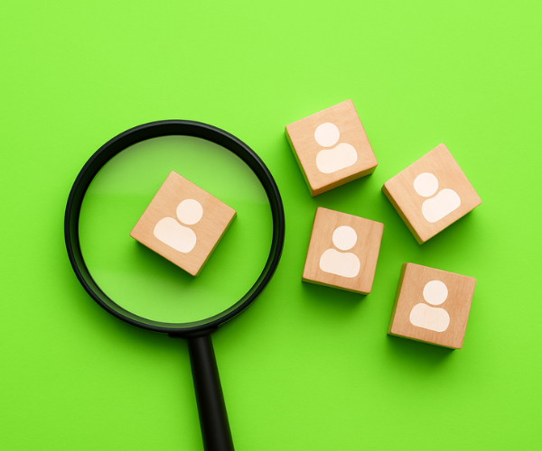 Photo of magnifying glass looking at wooden tiles with people illustrations