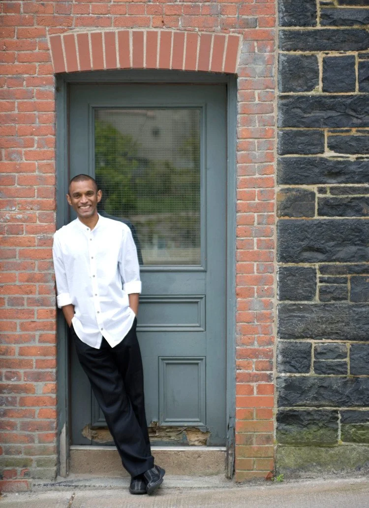 Dinuk Wijeratne Headshot leaning against a door frame