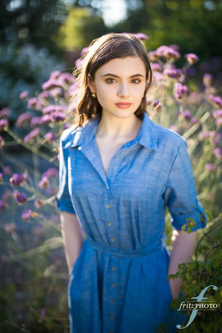 A young woman posing among flowers for her senior picture in Beaverton, Oregon at Jenkins Estate.