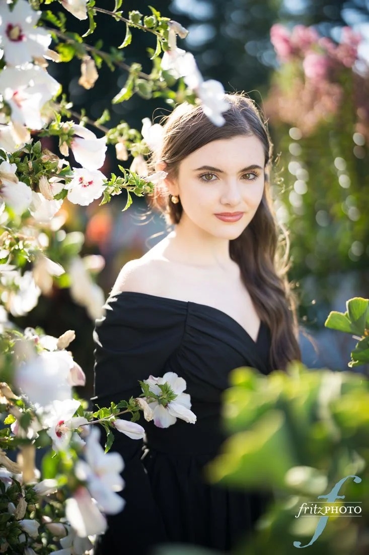 A young woman posing among flowers for her senior picture in Beaverton, Oregon.
