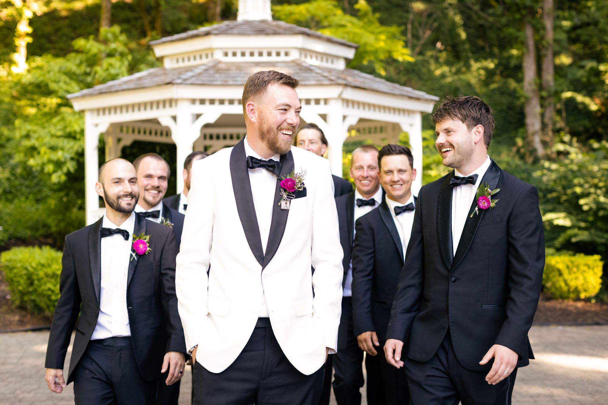 Wedding photo at Abernethy Center's Abigail's Garden of Group of men in tuxedos talking and smiling in front of a gazebo during a wedding.