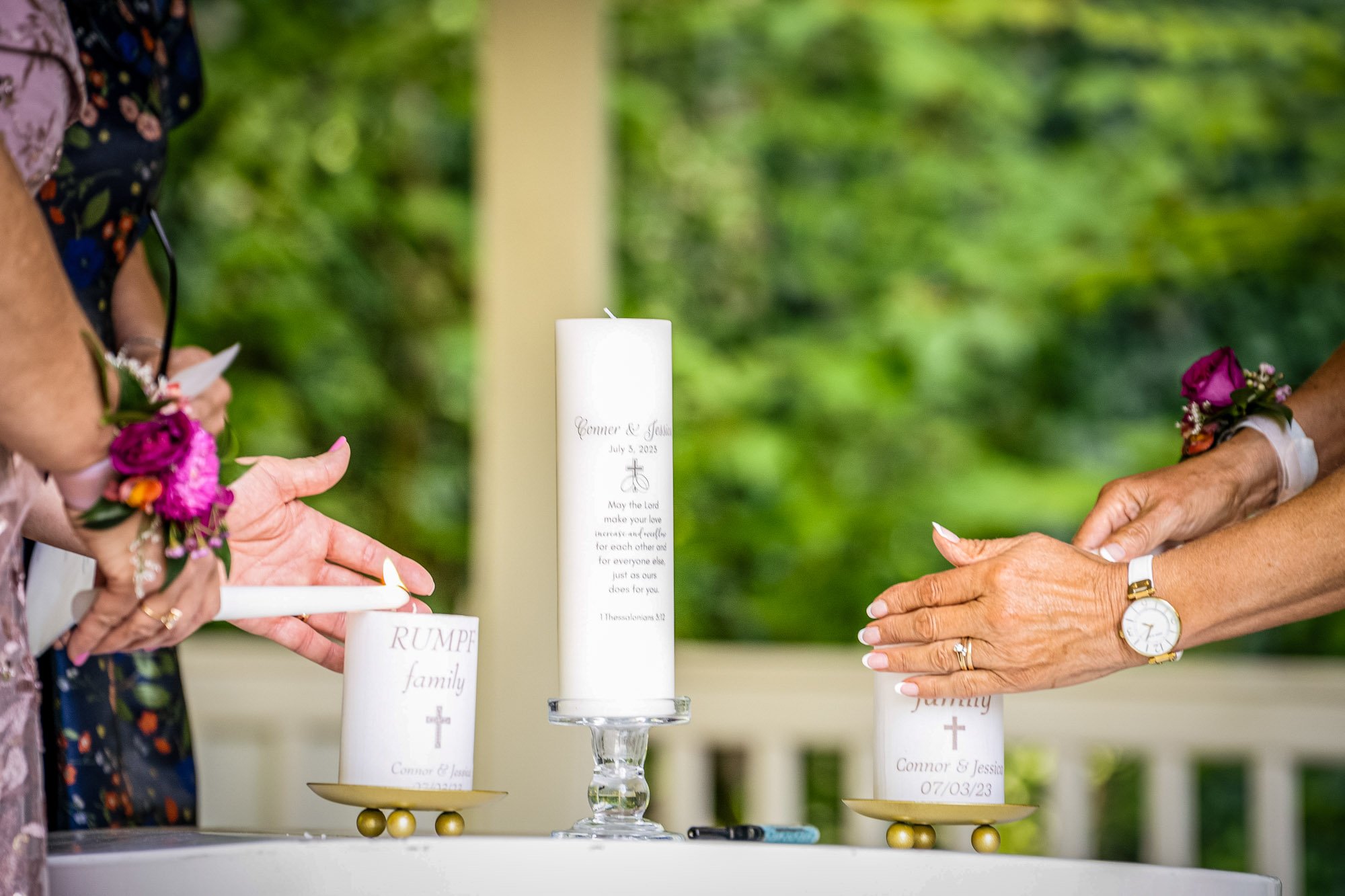 Wedding photography at Abernethy Center of Two women holding candles with wedding-related labels during a ceremony, with a green outdoor background.