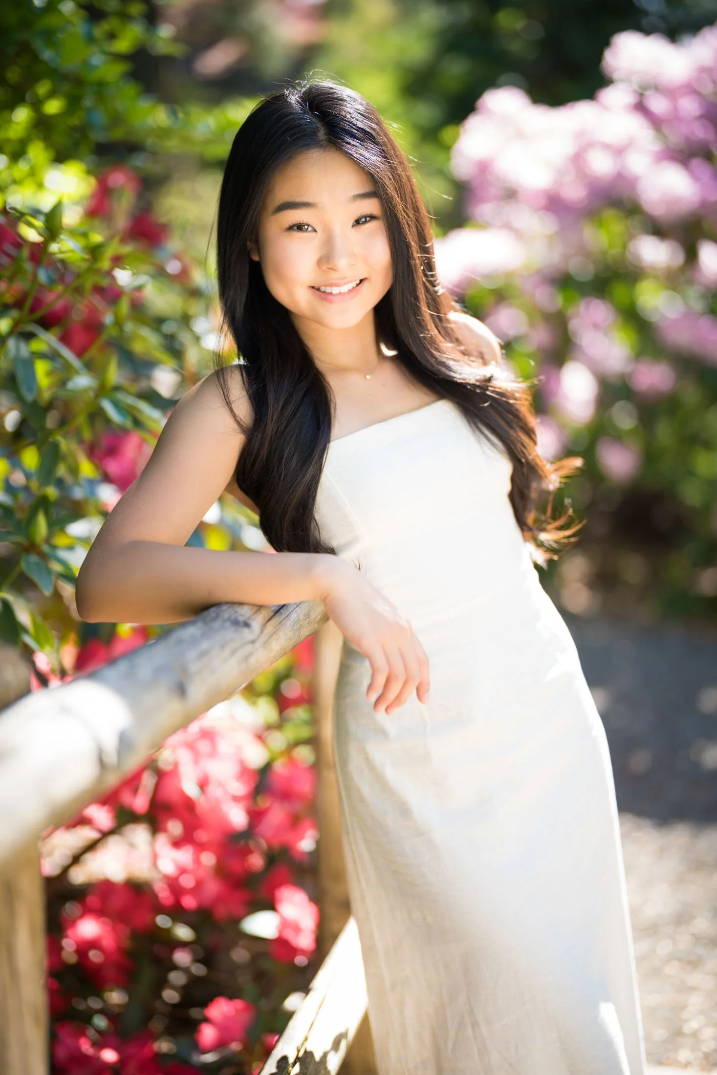 An Asian high school senior amongst rhododentron bushes for her senior photos.