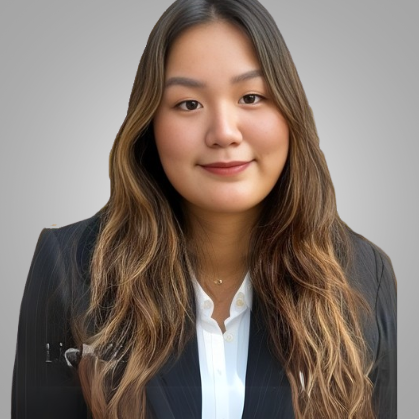 Professional portrait of a young woman with long wavy hair, wearing a dark pinstripe blazer and white blouse, smiling against a neutral gray background.