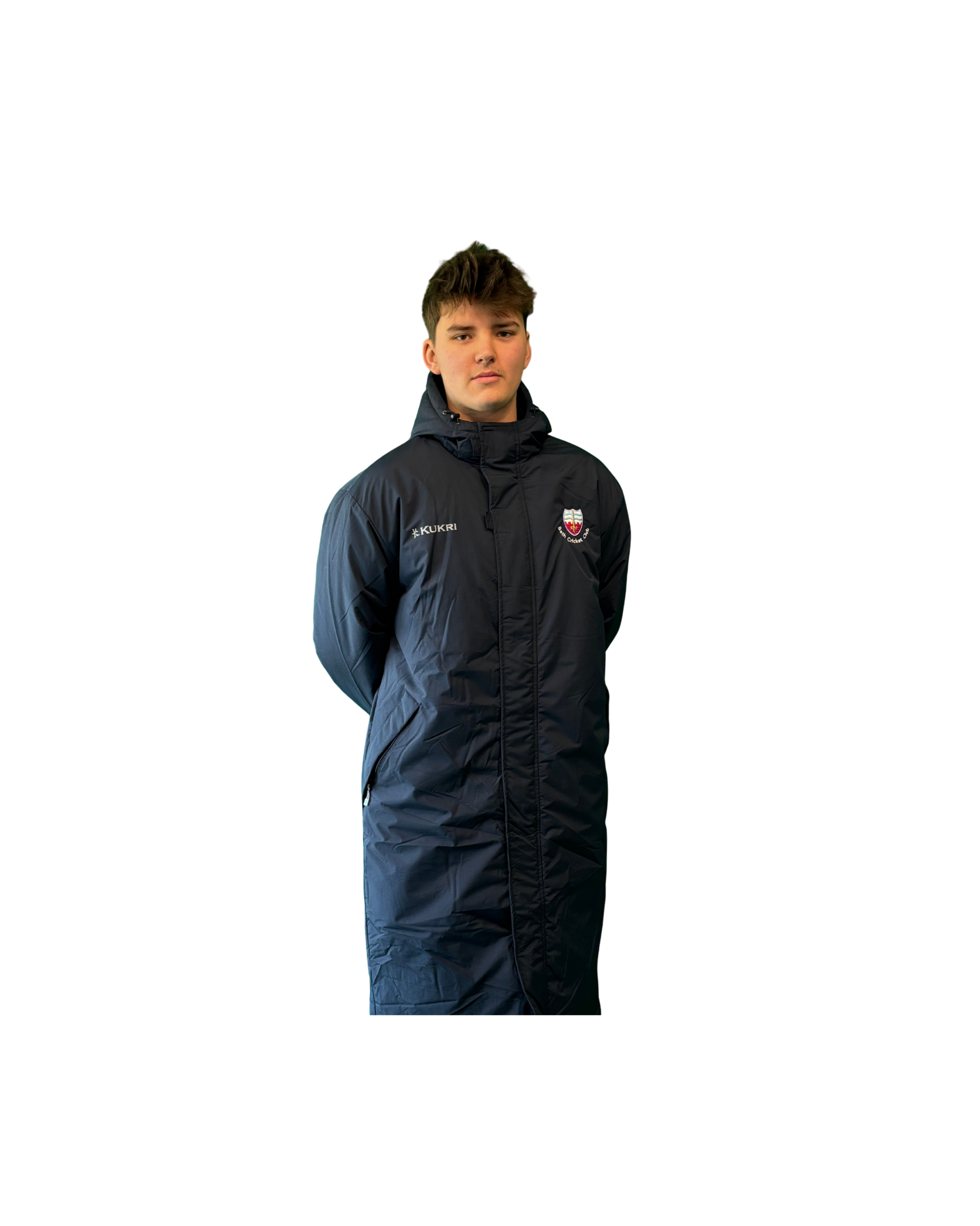 A young man wearing a black sports jacket with a crest and sponsor logos, standing against a black background.