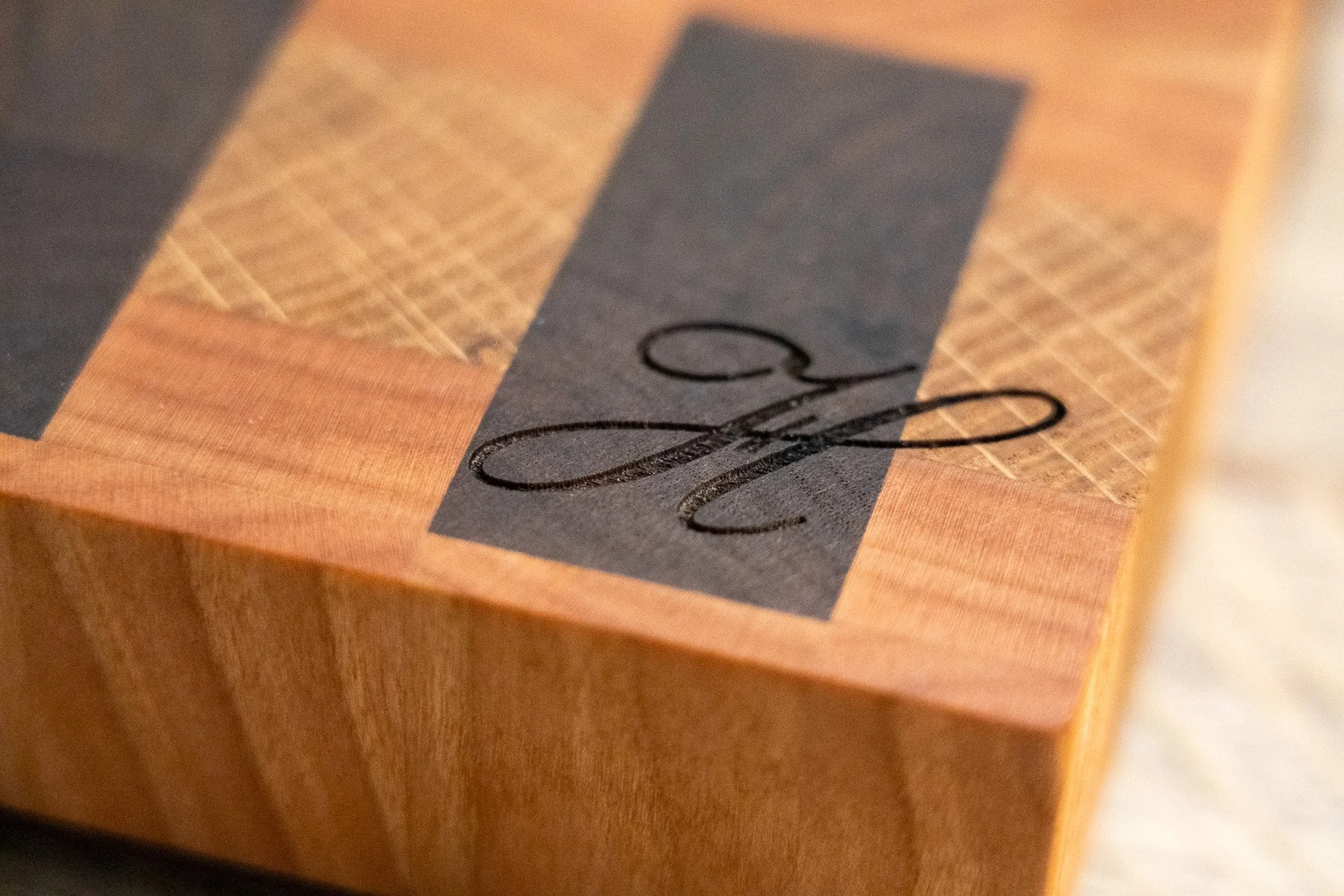 End grain cutting board featuring a laser engraved initial, customizing the piece.