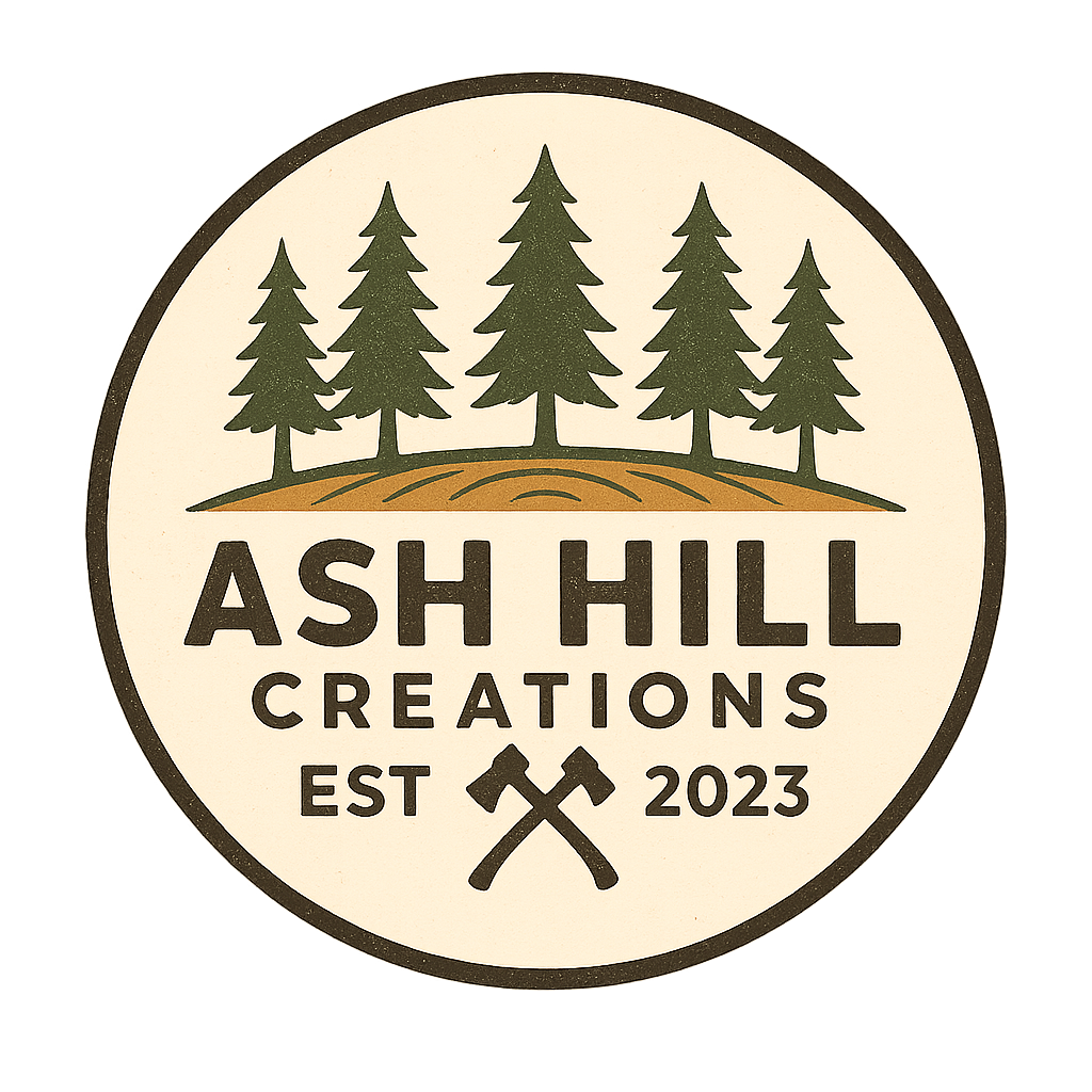Logo for Ash Hill Creations featuring five pine trees on a hill, with text indicating the company was established in 2023 and two crossed axes.