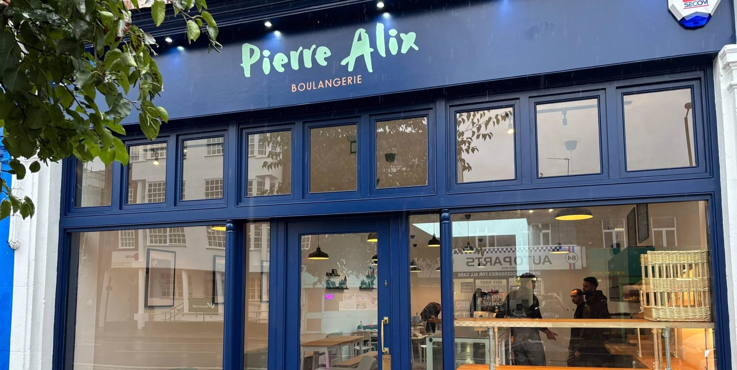 Exterior of "Pierre Alix Boulangerie" with blue facade and large windows.