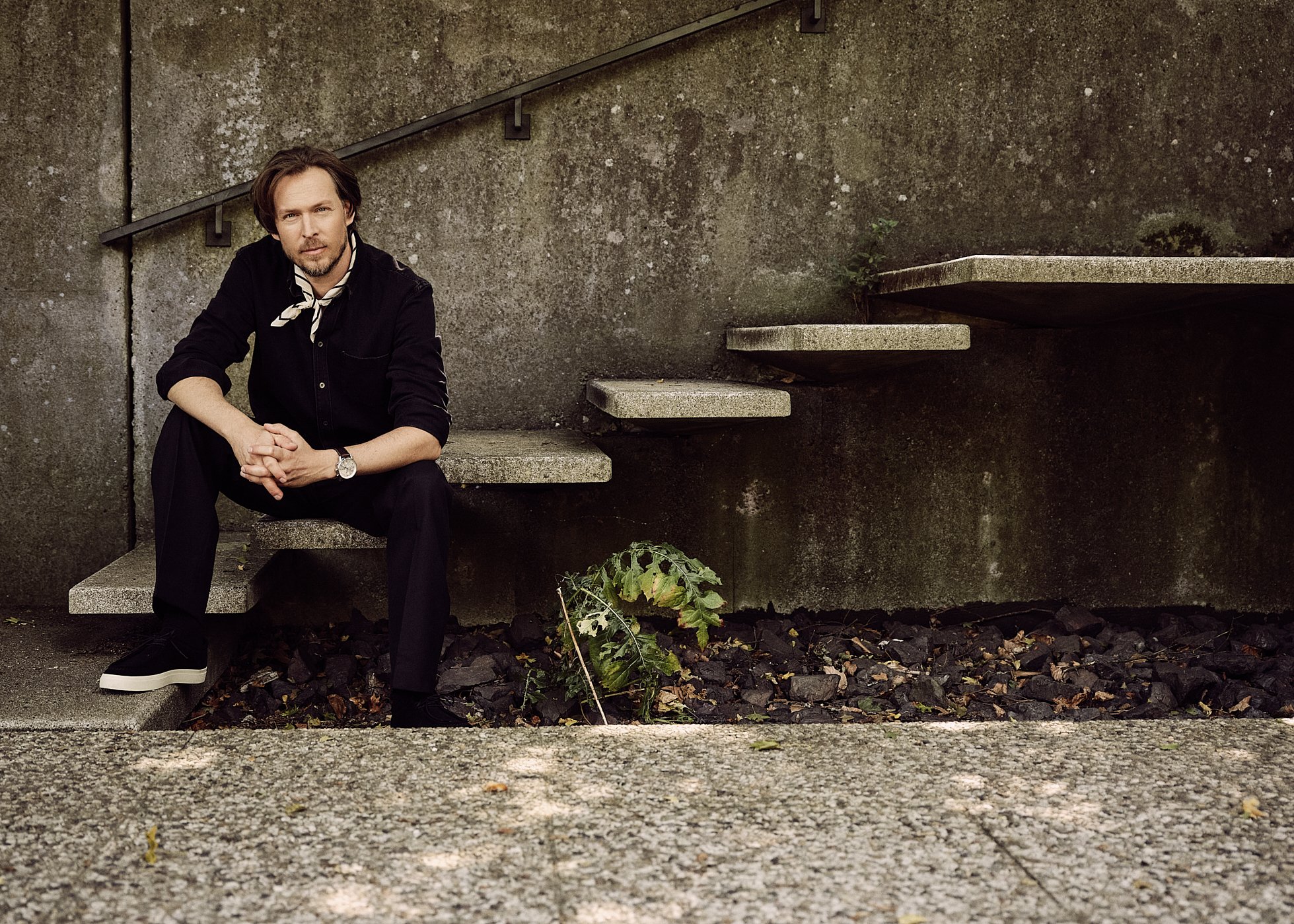 Maensch sitze auf einer Treppe vor einer grauen Wand