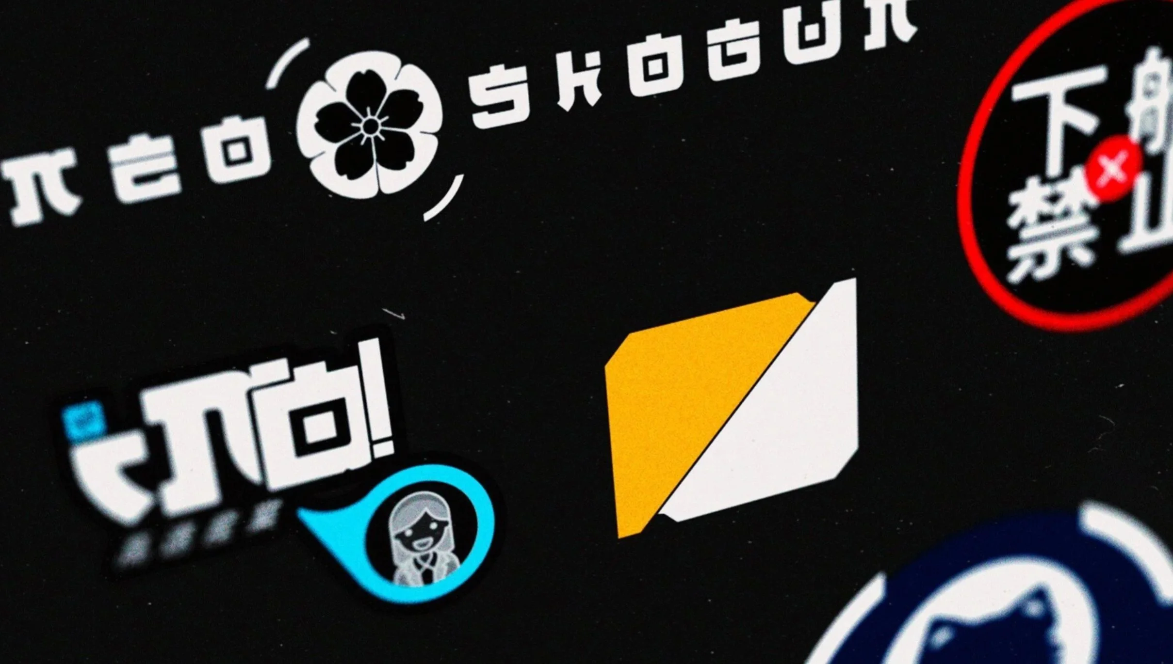 Close-up of a black surface with various colorful icons, including a white flower, a yellow arrow, a blue smiling woman, and Japanese and English characters.