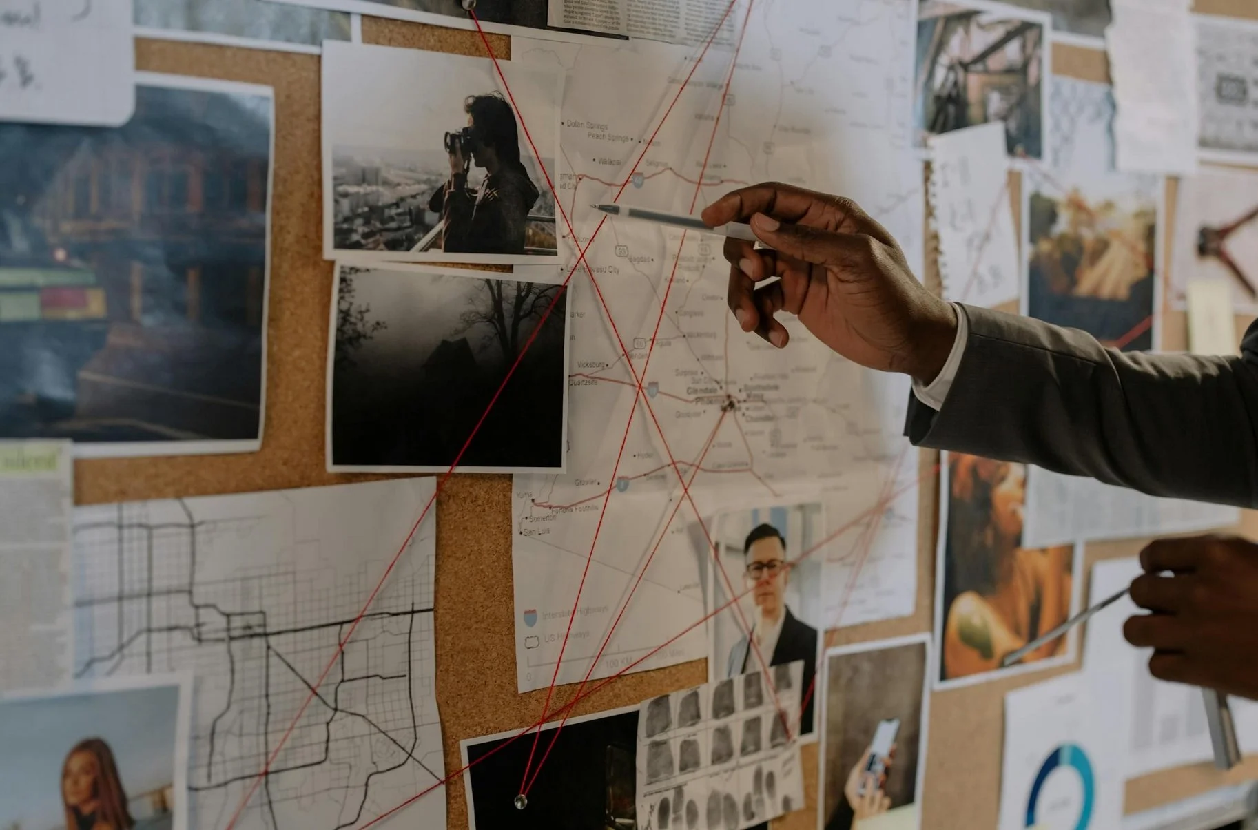 an image of a crime board, exemplifying how complex character design research can be, as analogy. Close-up, hand pointing at an overlap of reference and maps.