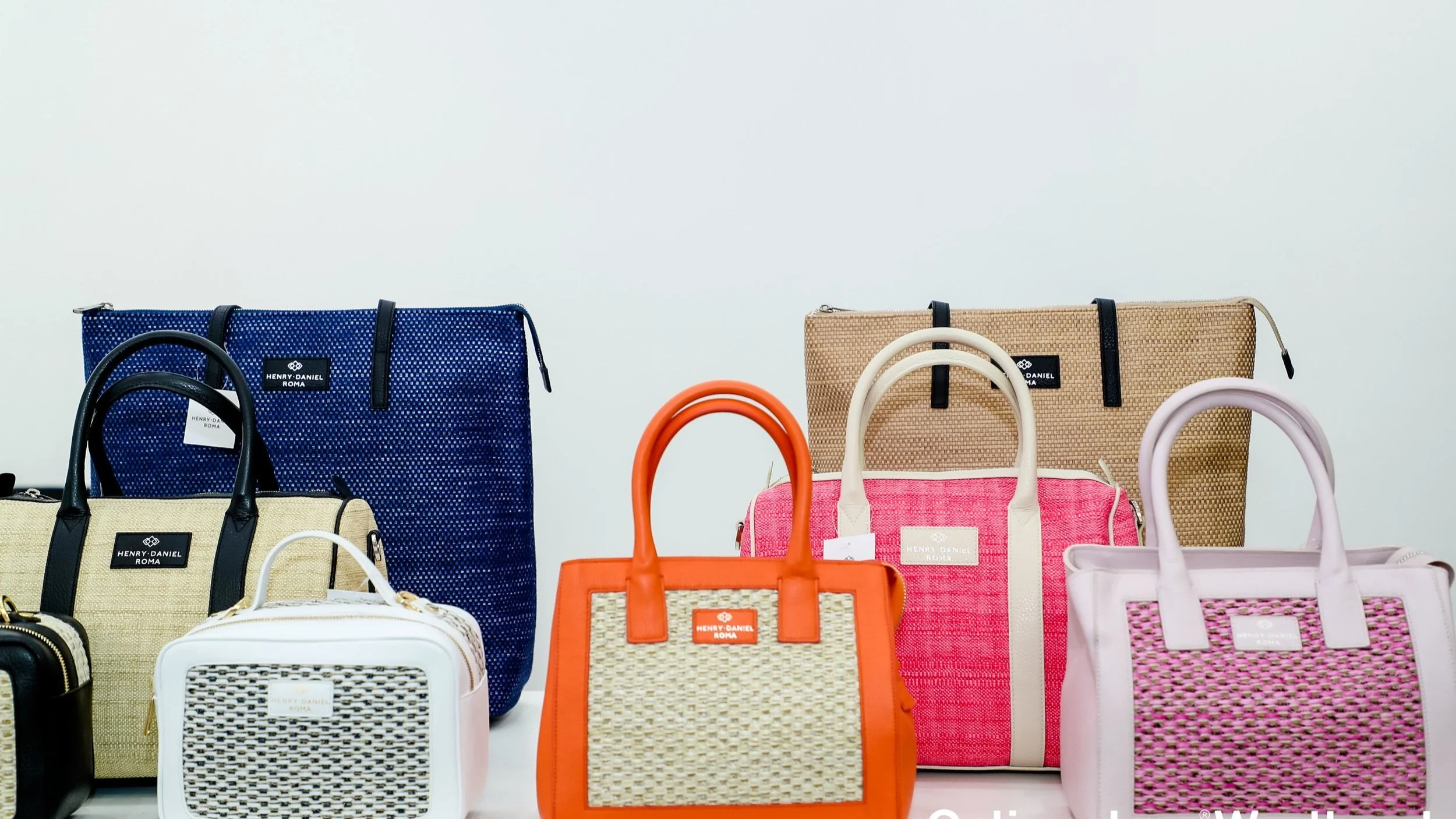 Assorted colorful handbags and tote bags on display against a plain background.