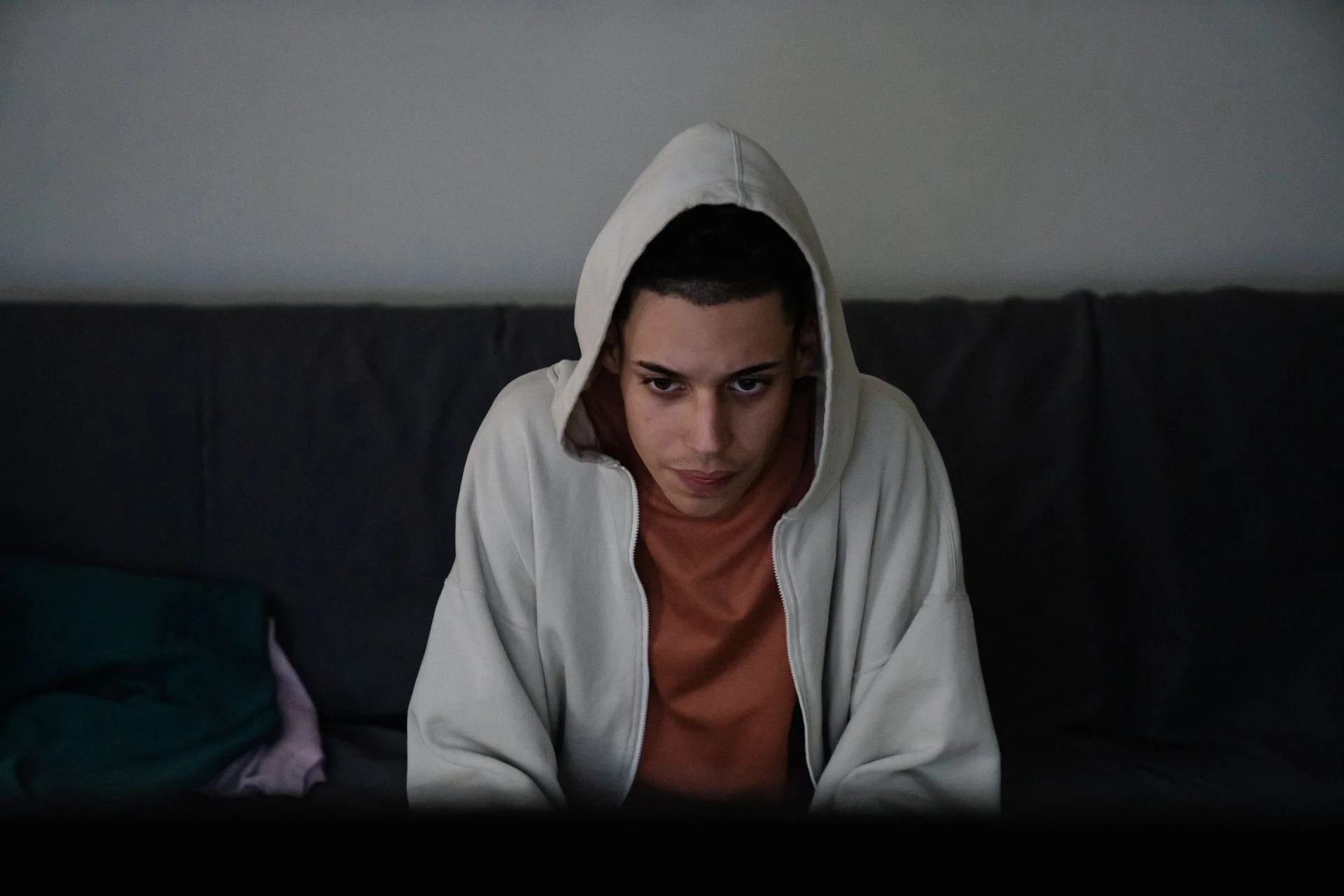 A person sitting on a sofa, staring ahead with a tired, blank expression