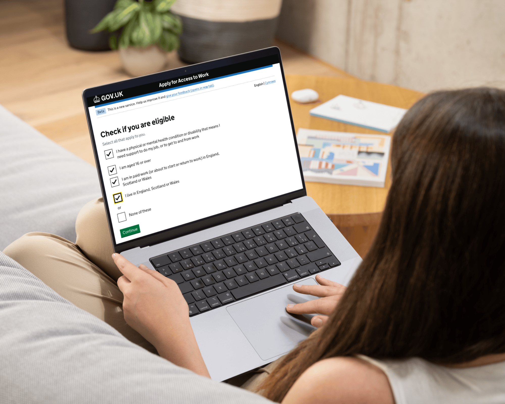 A person sitting on a sofa applying to Access to Work on a laptop