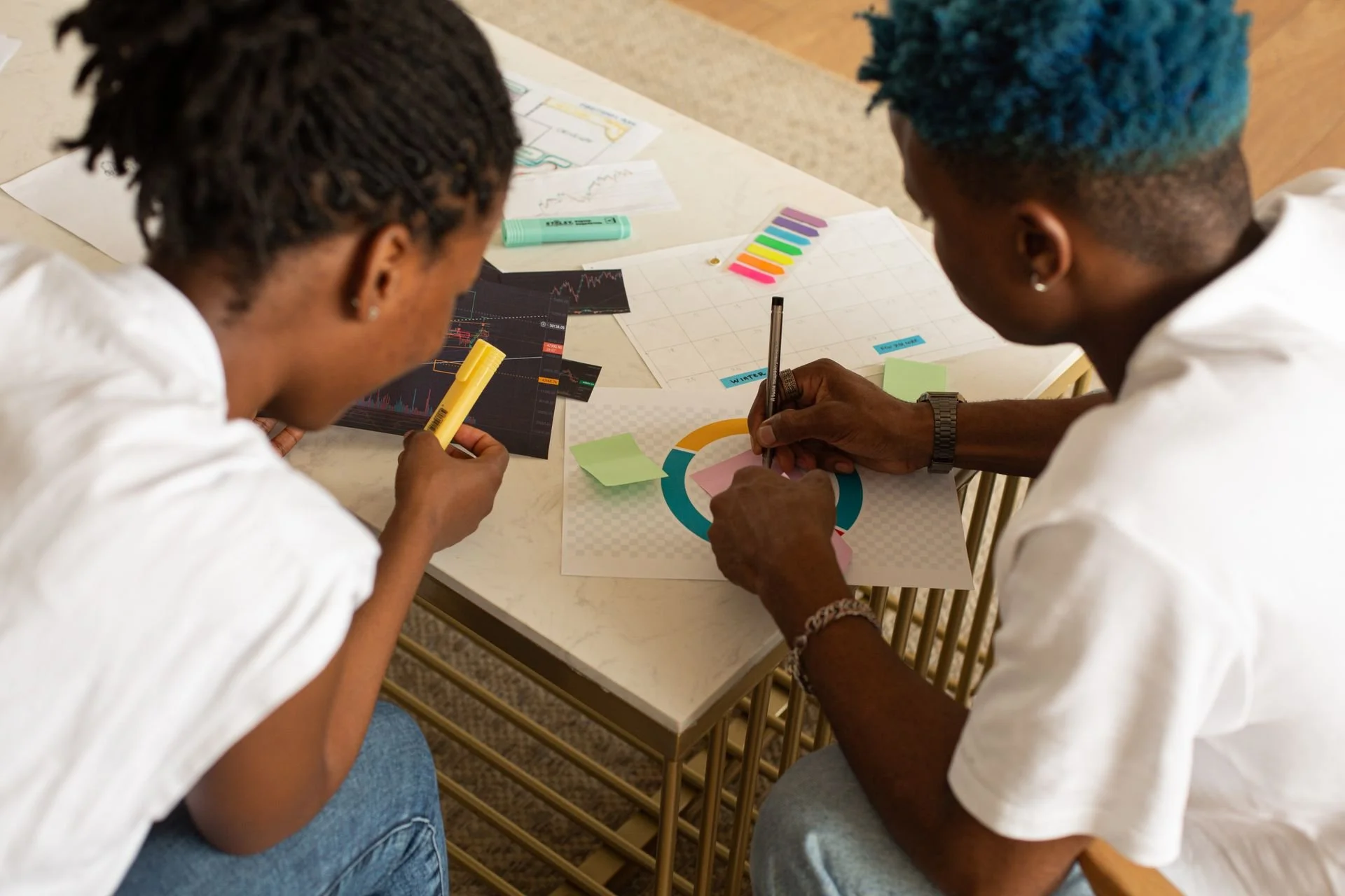 Two people sitting together at a table, one taking notes while the other talks