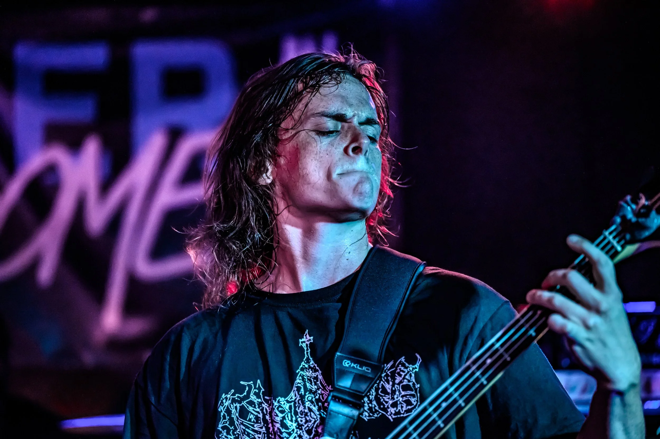 Reece Maopolski from the band Brotality, dark background and colorful stage lighting.