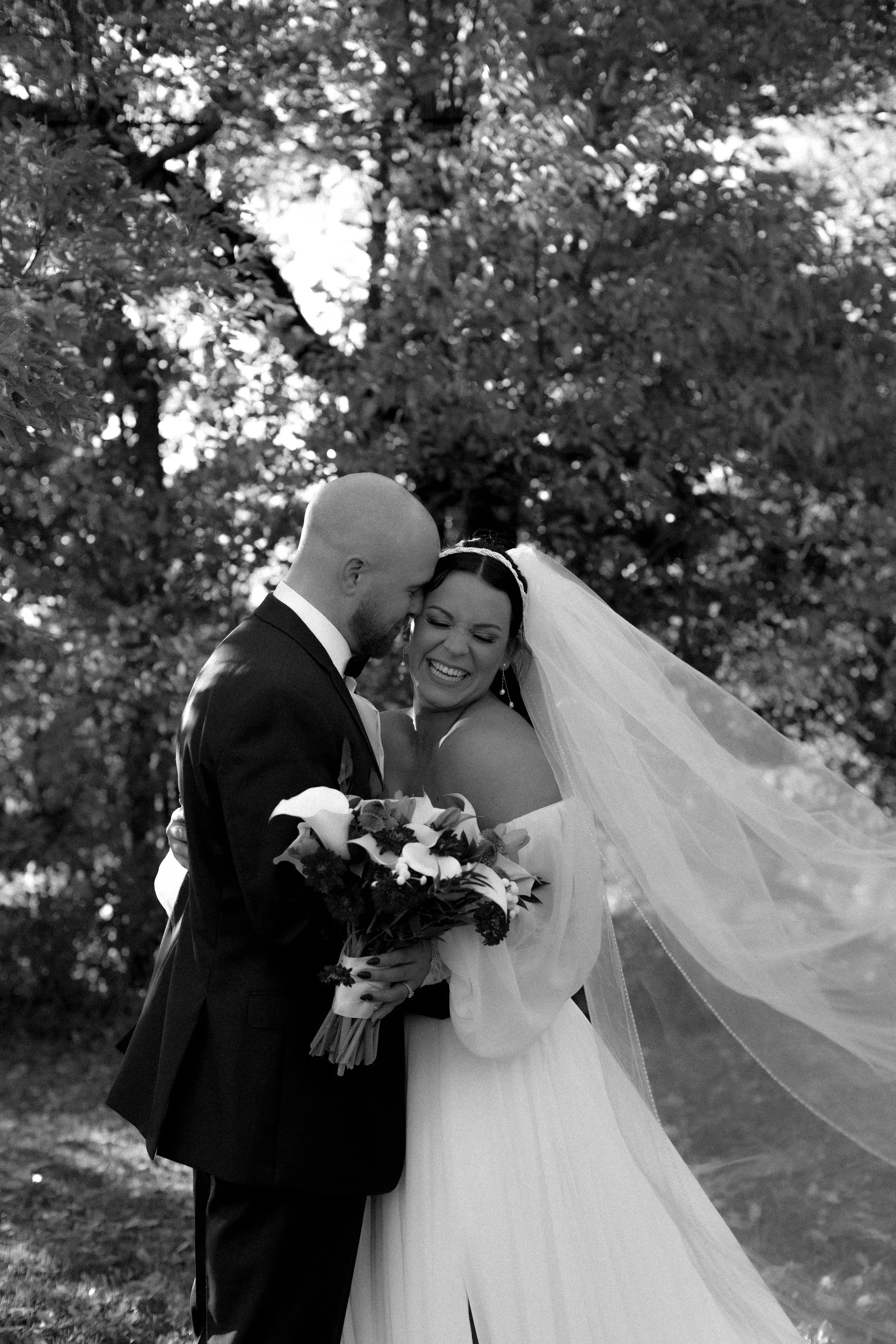 A black and white photo of a bride and groom sharing a tender moment outdoors, during their Buffalo New York Wedding