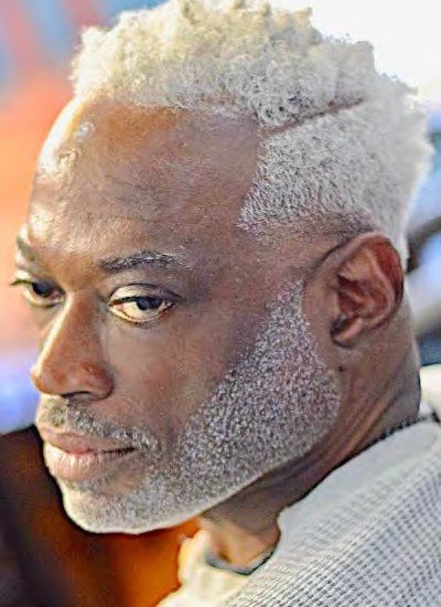 A man with a short, platinum blonde hairstyle and matching beard and hair dye on his face.