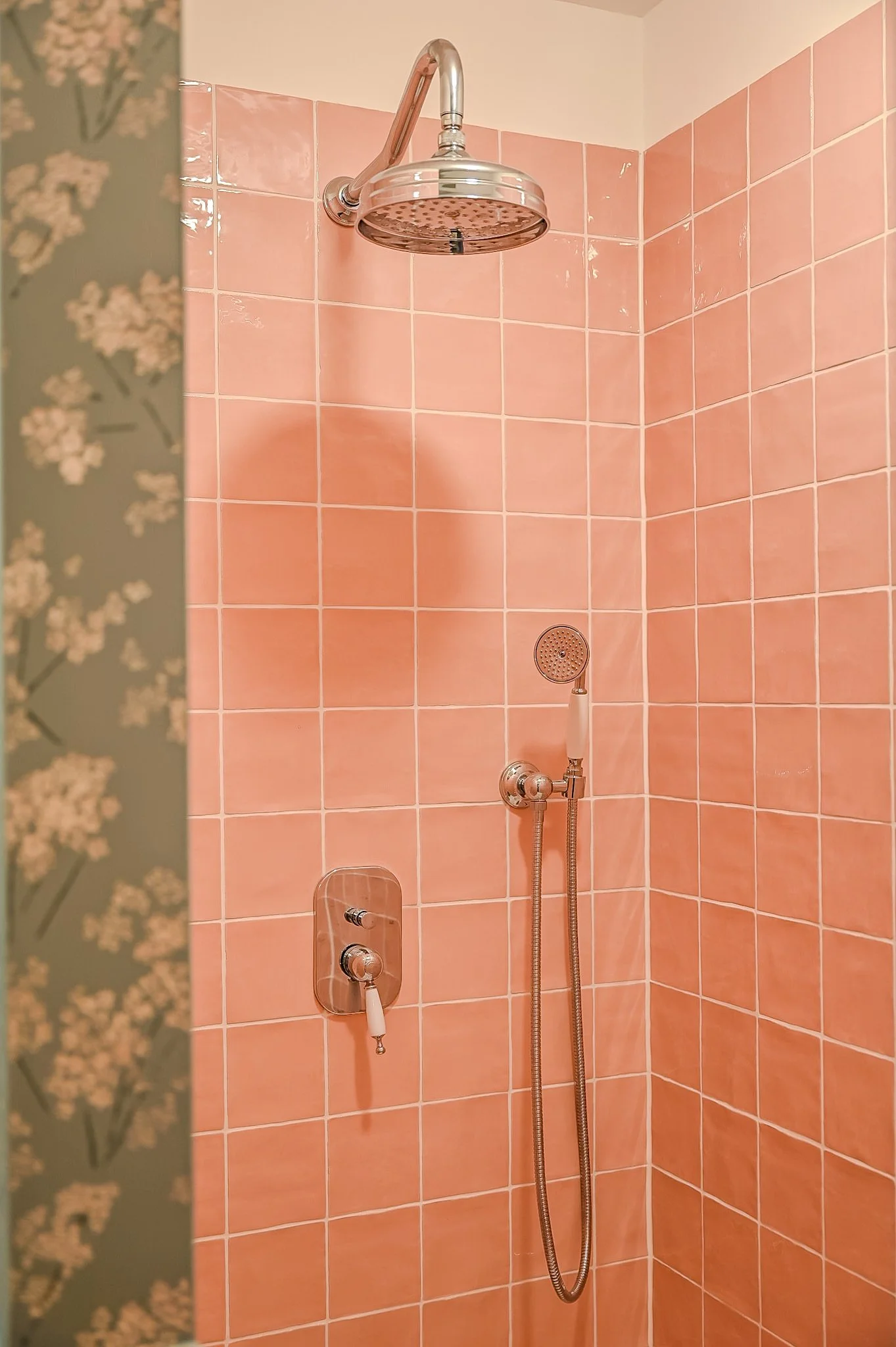 Dusche mit pinkfarbenen Fliesen, Regenduschkopf und Handbrause.