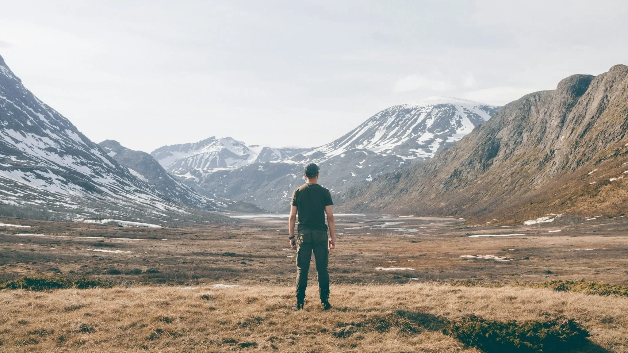 Man standing in a mountain valley symbolizing uncertainty about the future self and life changes.
