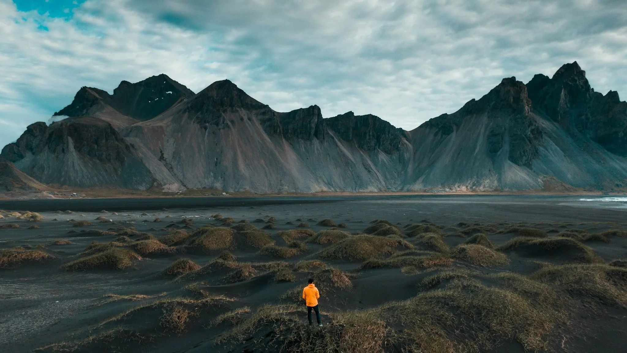 Man standing in a vast natural landscape, reflecting on perspective and long-term understanding beyond daily news.