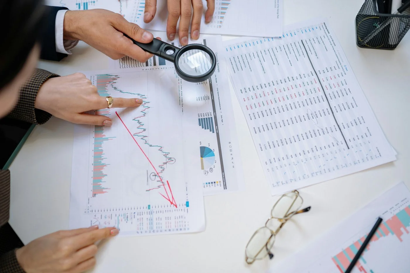 Magnifying glass held over financial charts and data — representing critical analysis of annuity products and their real costs for FIRE investors.