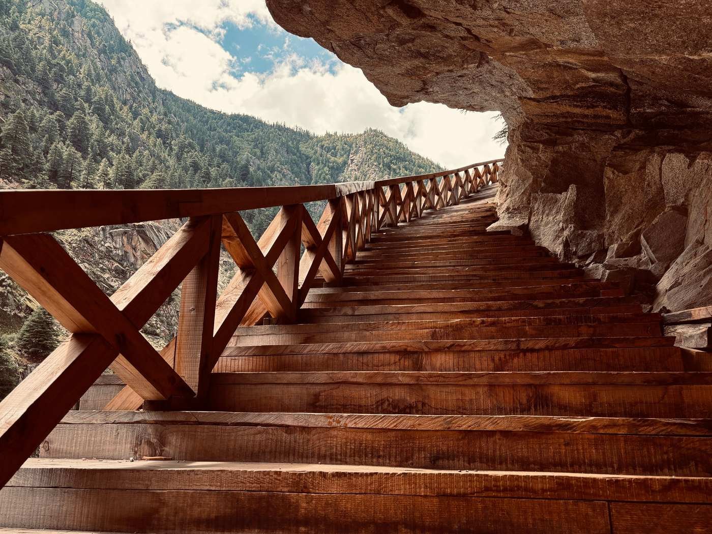 Wooden staircase built into a mountain rock face, representing the one-step-at-a-time 1% savings method.