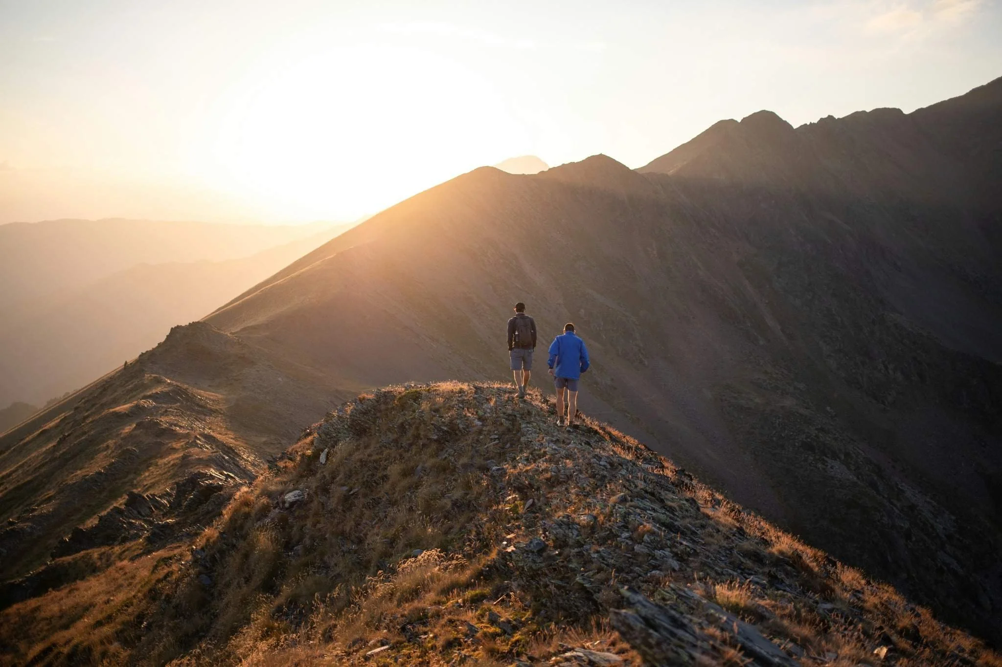 Two hikers ascending a mountain ridge symbolizing progress through the stages of financial independence.