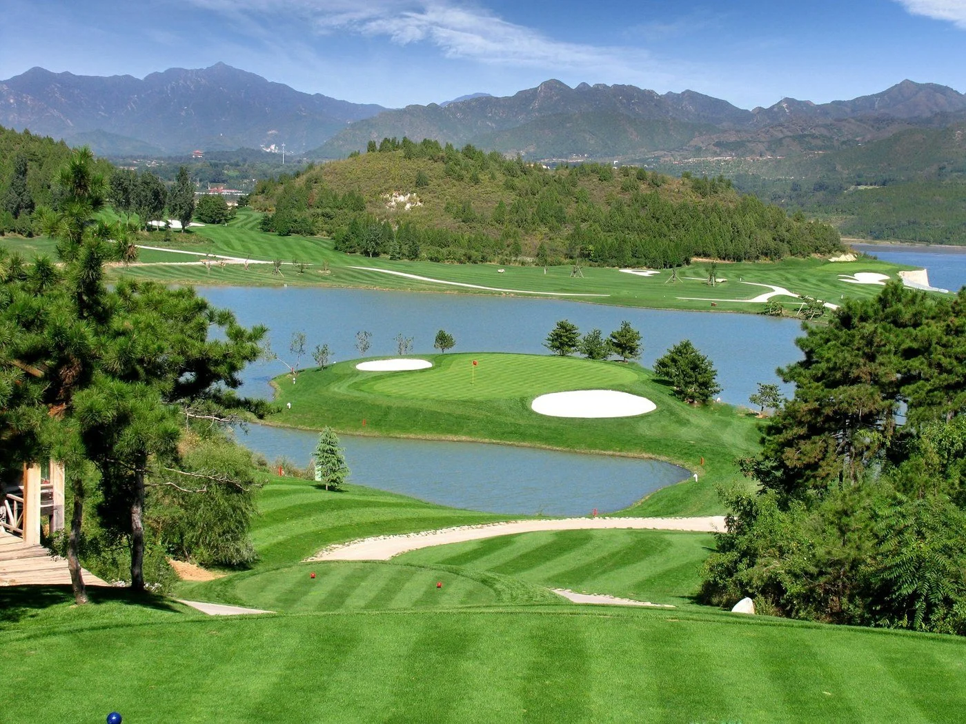 Scenic golf course surrounded by water and mountains representing well-earned early retirement leisure.