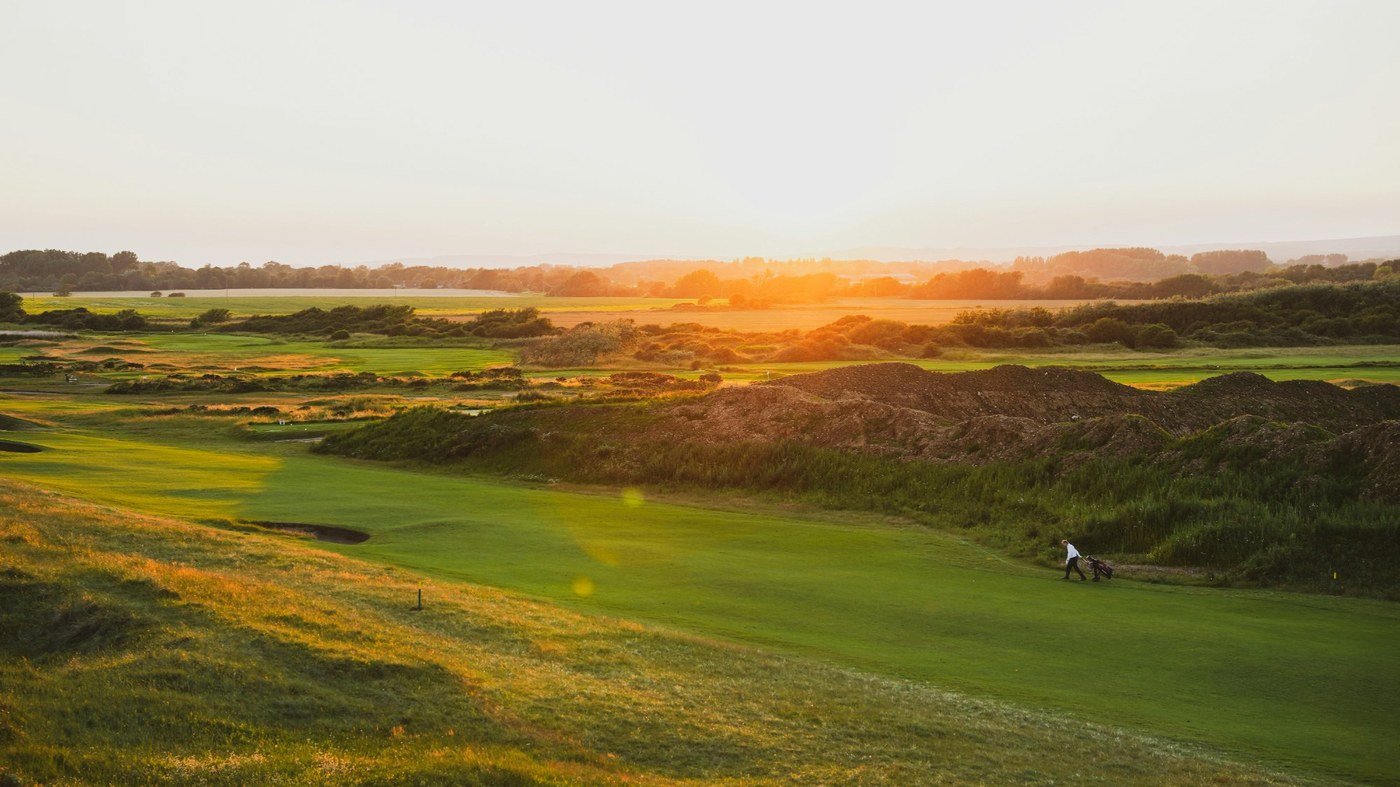 Golfer walking on scenic course at sunset representing early retirement freedom and financial independence lifestyle.