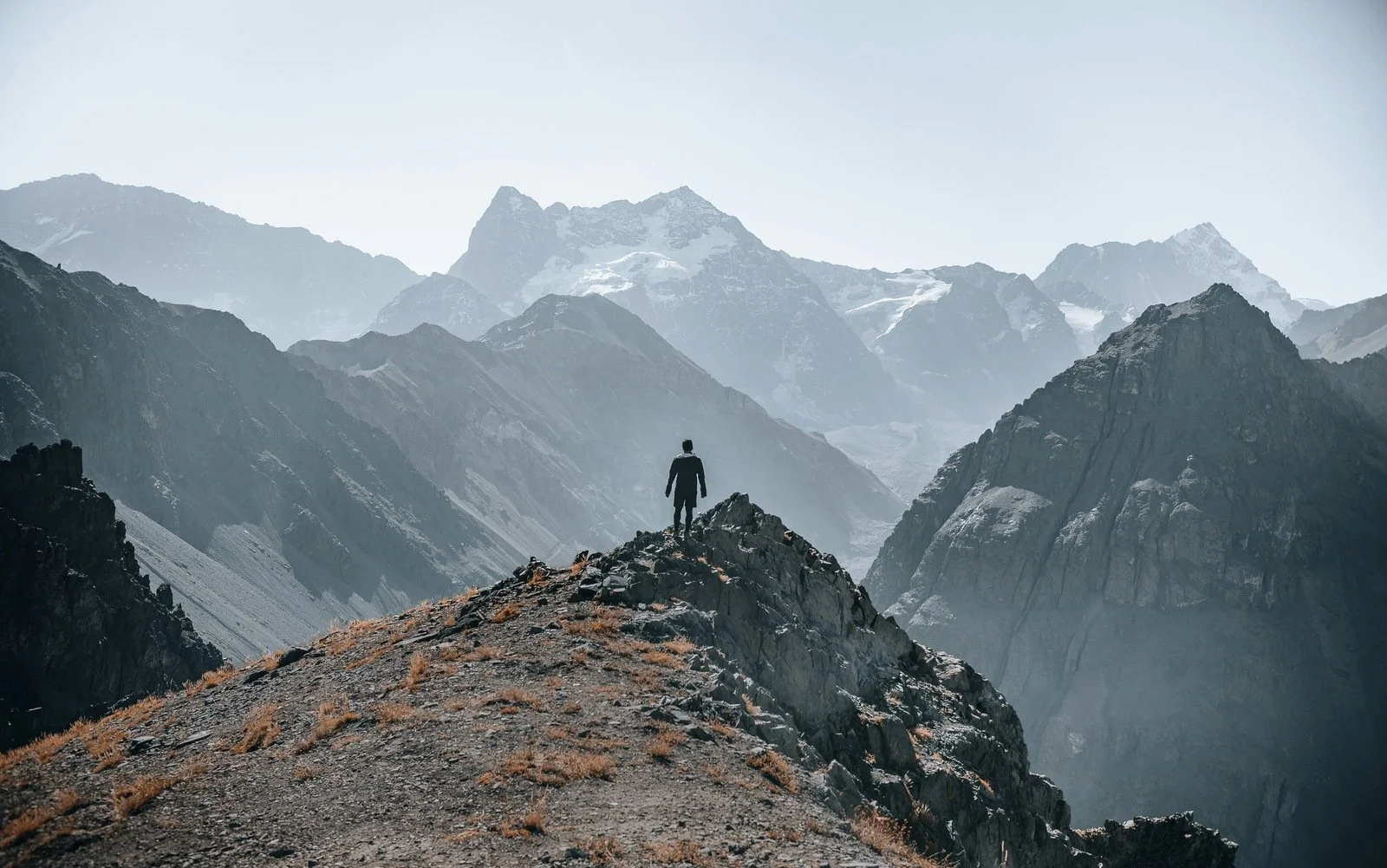Man standing alone on mountain peak looking at vast landscape — financial independence and life purpose.