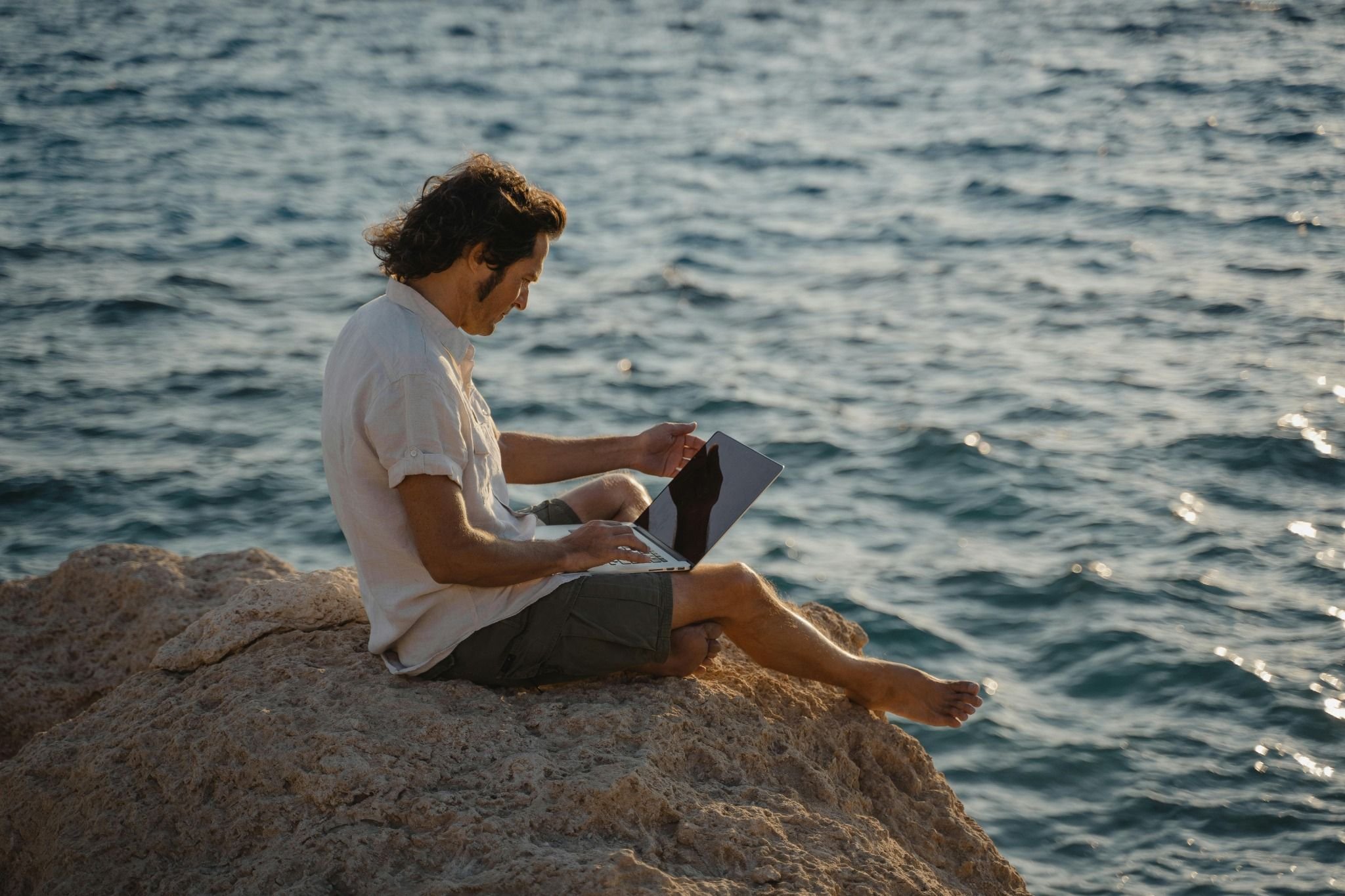 Man working on laptop by the sea representing early retirement planning and flexible FIRE lifestyle.