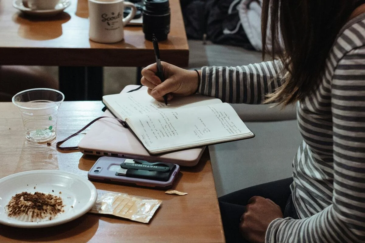 Woman writing in notebook planning her savings rate and budget for Financial Independence.
