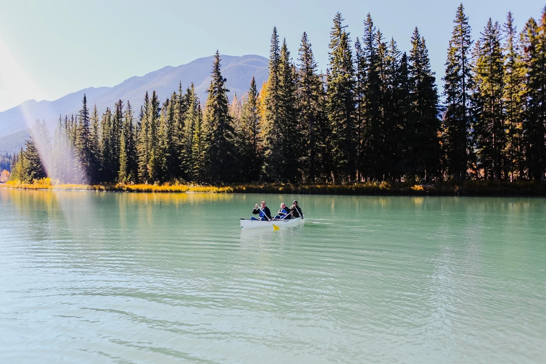 Three people canoeing on a calm mountain lake in autumn, symbolizing the active, capable years that health makes possible in retirement.