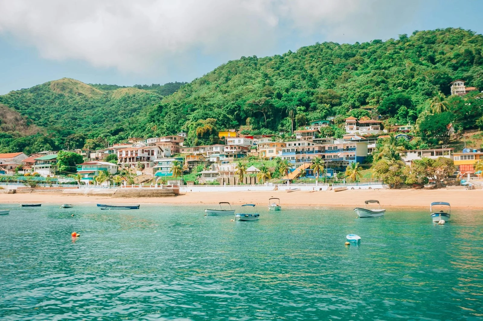 Tropical beach town with colourful houses and boats — representing the appeal of retiring abroad in Latin America through geographic arbitrage.