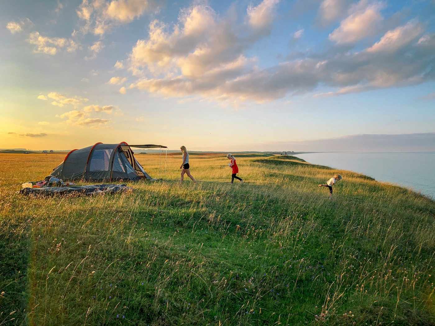 Mother and children camping near the sea at sunset — mini-retirement as annual family time during FIRE accumulation phase.