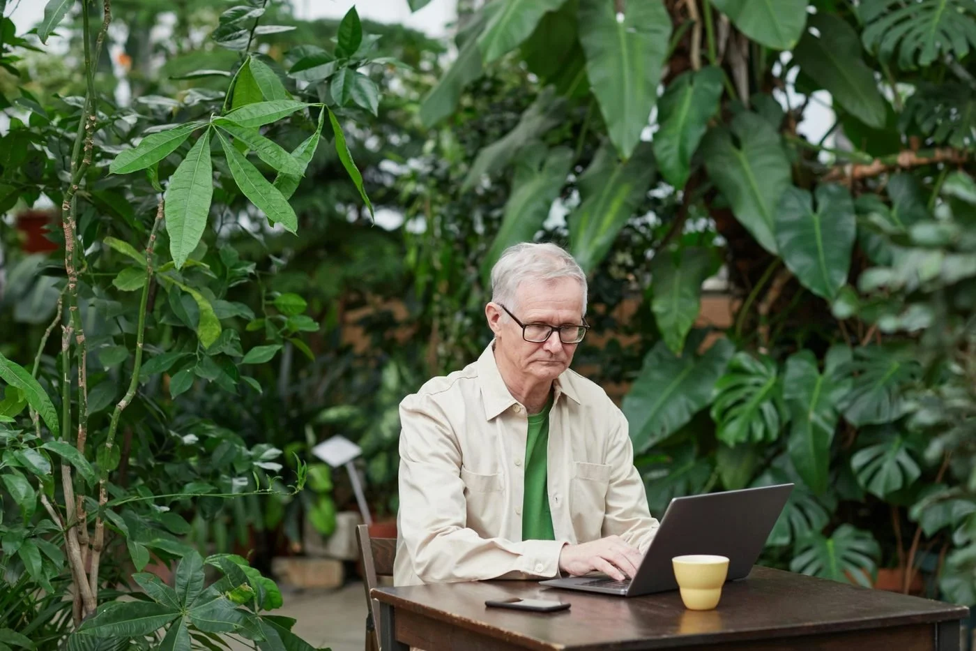 Older professional working on laptop in outdoor cafe setting illustrating flexible early retirement work options.