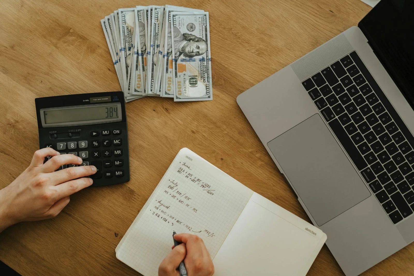Planning retirement withdrawals with calculator, cash and laptop.