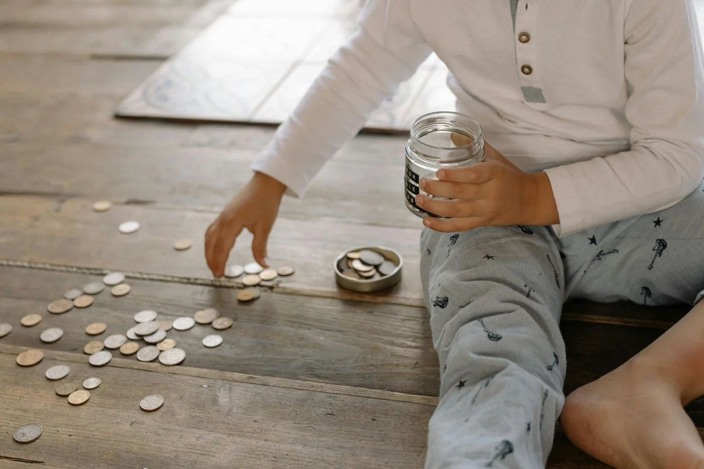 Person collecting coins into a jar representing budgeting and saving for financial independence.