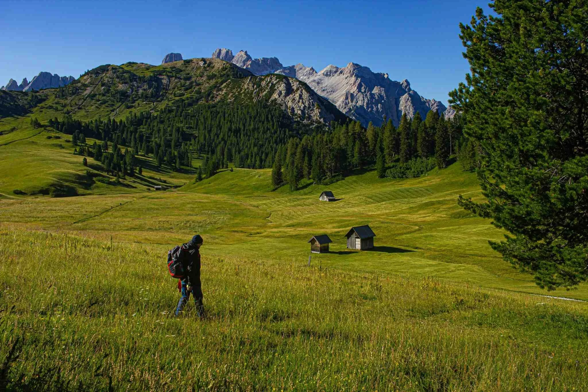 Person walking through a peaceful mountain valley symbolizing simplicity, reflection, and freedom beyond material comparison.