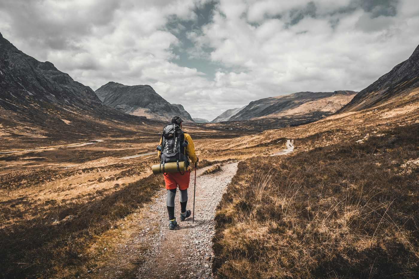 Man hiking uphill on a rugged trail through nature, symbolizing the long, steady climb of the Financial Independence journey.