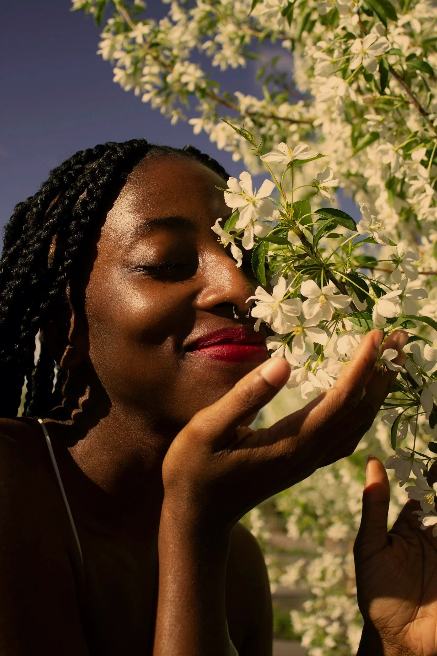 Deep brown skinned woman smelling flowers