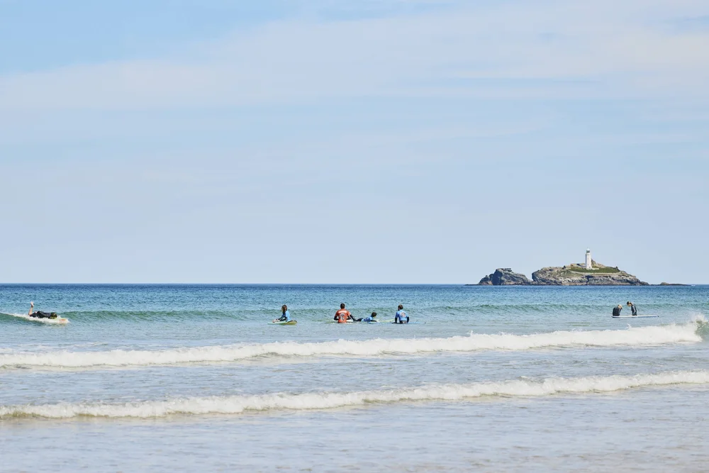 Surfers enjoying a surf lesson in Cornwall, a popular gift experience