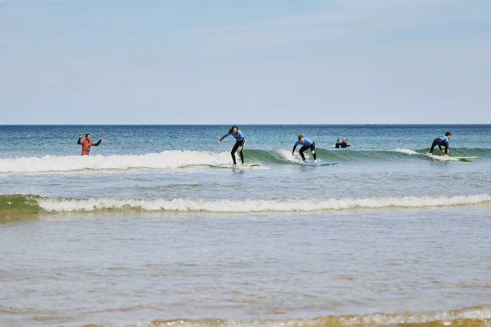 Family riding an unbroken wave together during a family surf lesson in Cornwall