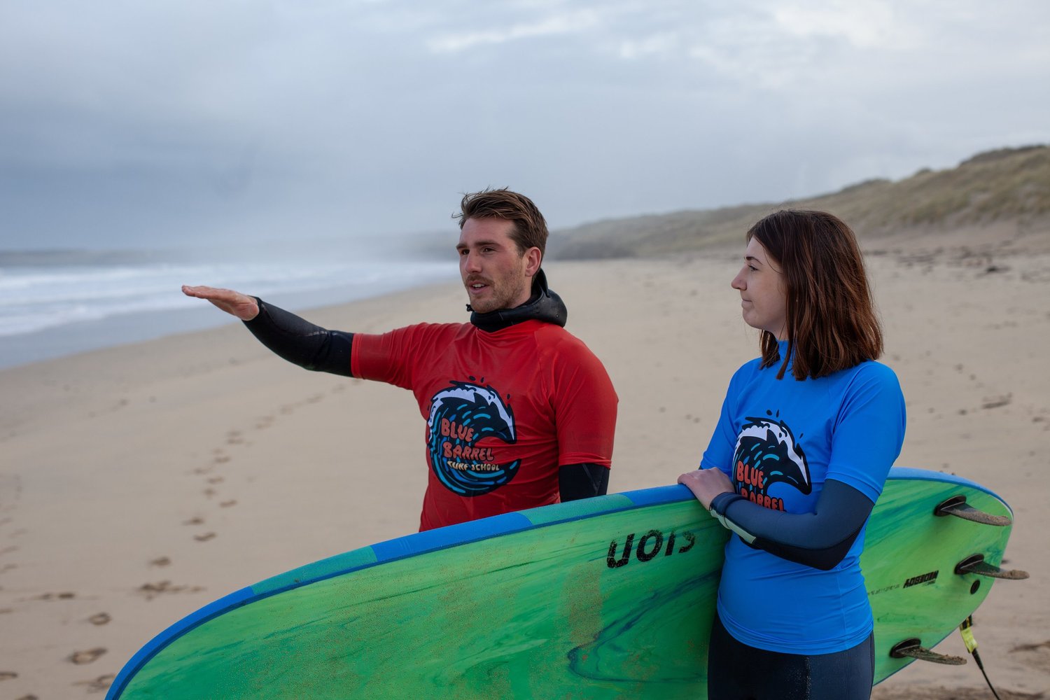 Surf coach talking with a surfer on the beach before a private surf lesson in Cornwall