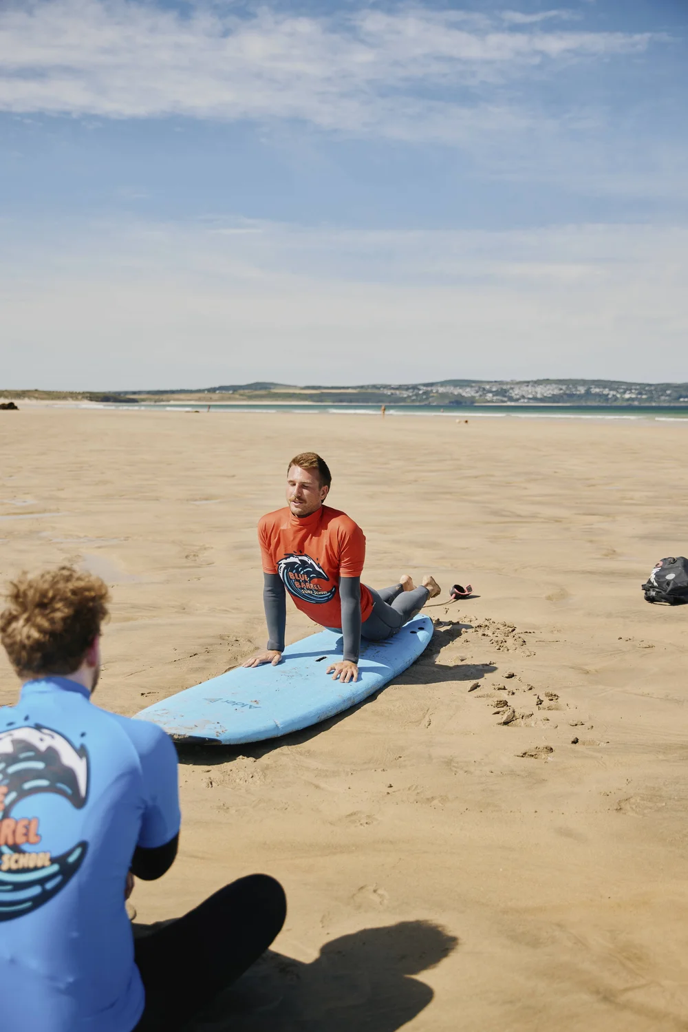 Beginner surf lesson practising pop-ups on the sand in Cornwall
