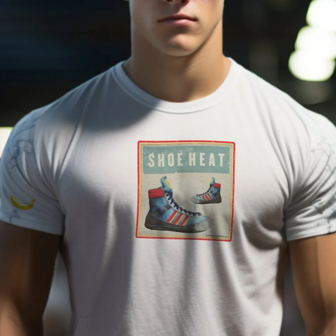 Man wearing white t-shirt with vintage sneaker graphic and "Shoe Heat" text, featuring blue sneakers with red and rainbow stripes, and a small banana icon on the sleeve.