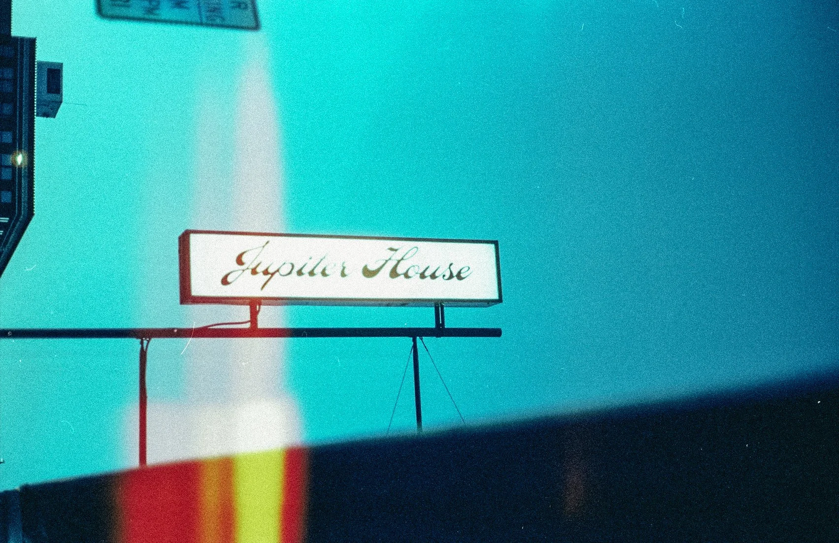 Retro-style sign with 'Jupiter House' text against a blue sky.