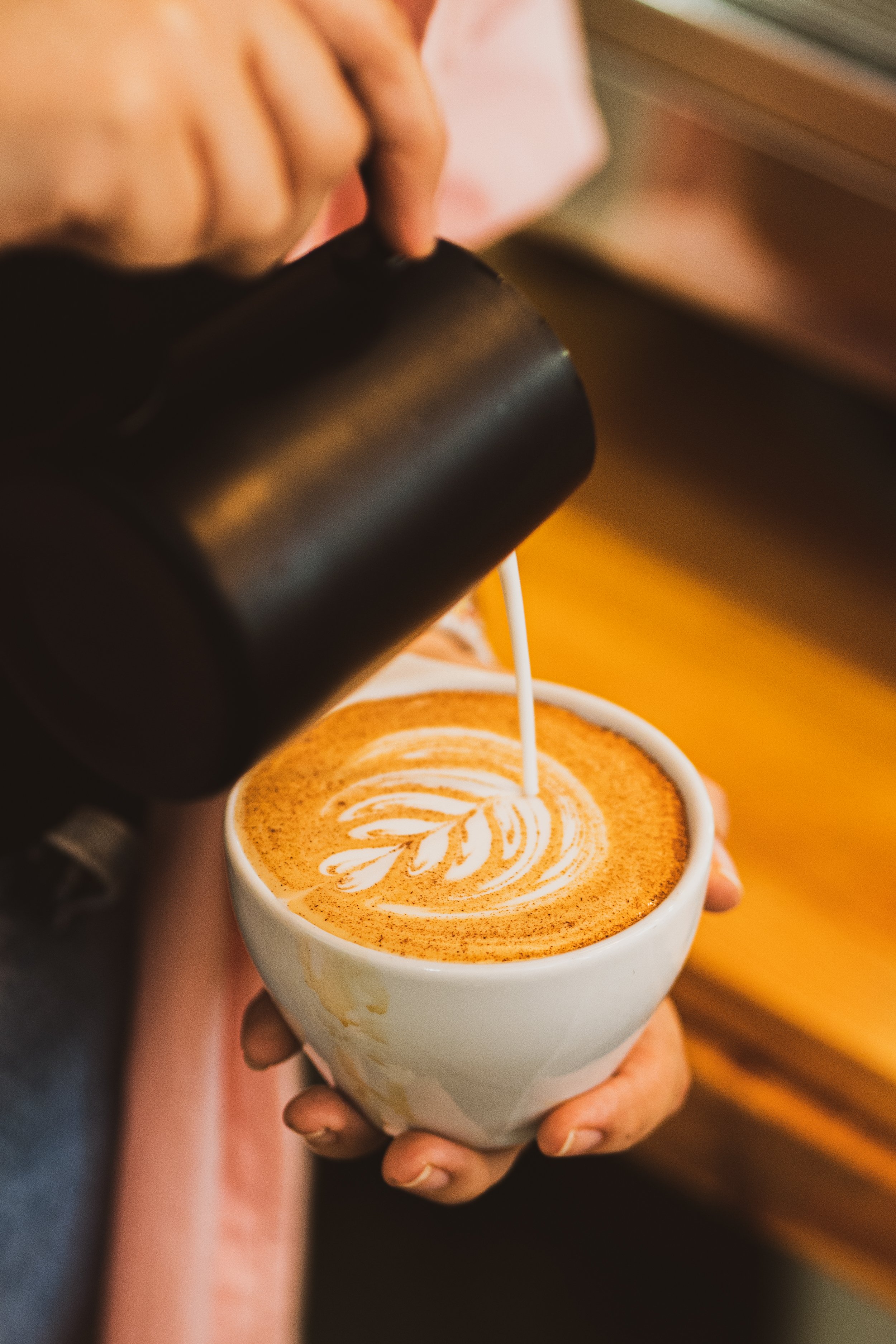 Barista pouring latte art into a cup of coffee