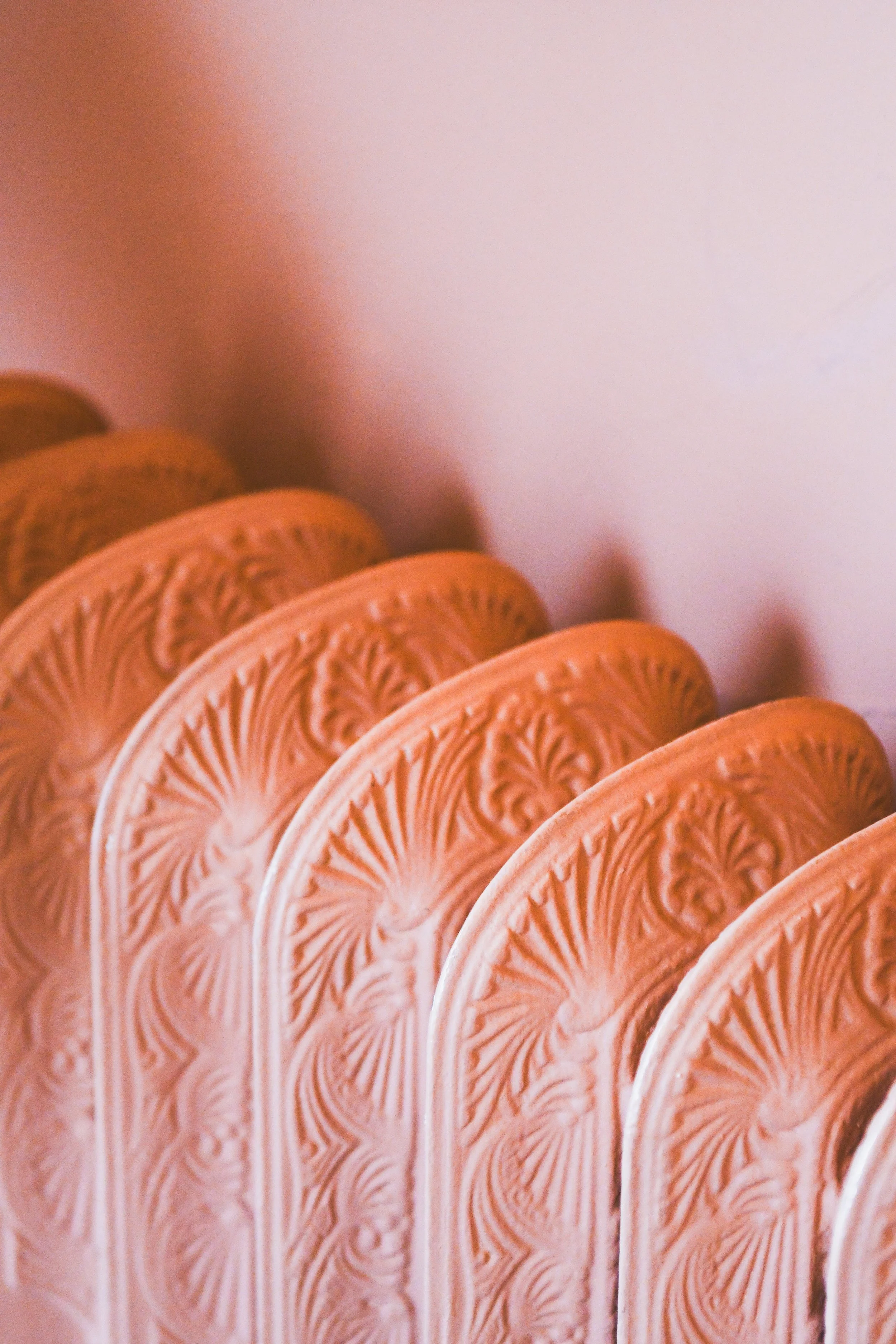 A close-up of a row of decorative vintage plates with intricate embossed patterns, arranged vertically.